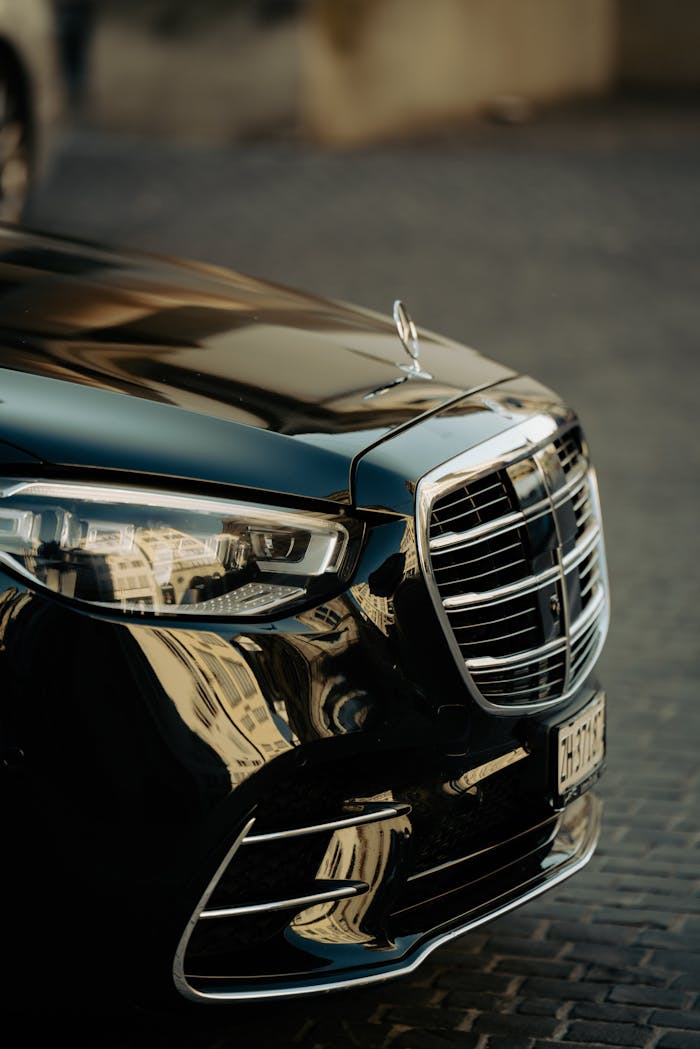 Close-up of a luxury black cars front showcasing its sleek design and reflective finish.